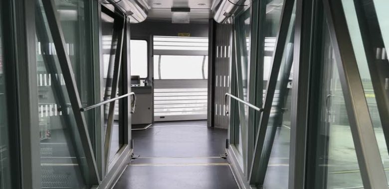 istockphoto-2133465470-640×640 First-person POV walking inside empty and inoperative passenger boarding bridge without airplane
